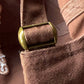 Close-up of a brown textured fabric with a gold metal buckle.
