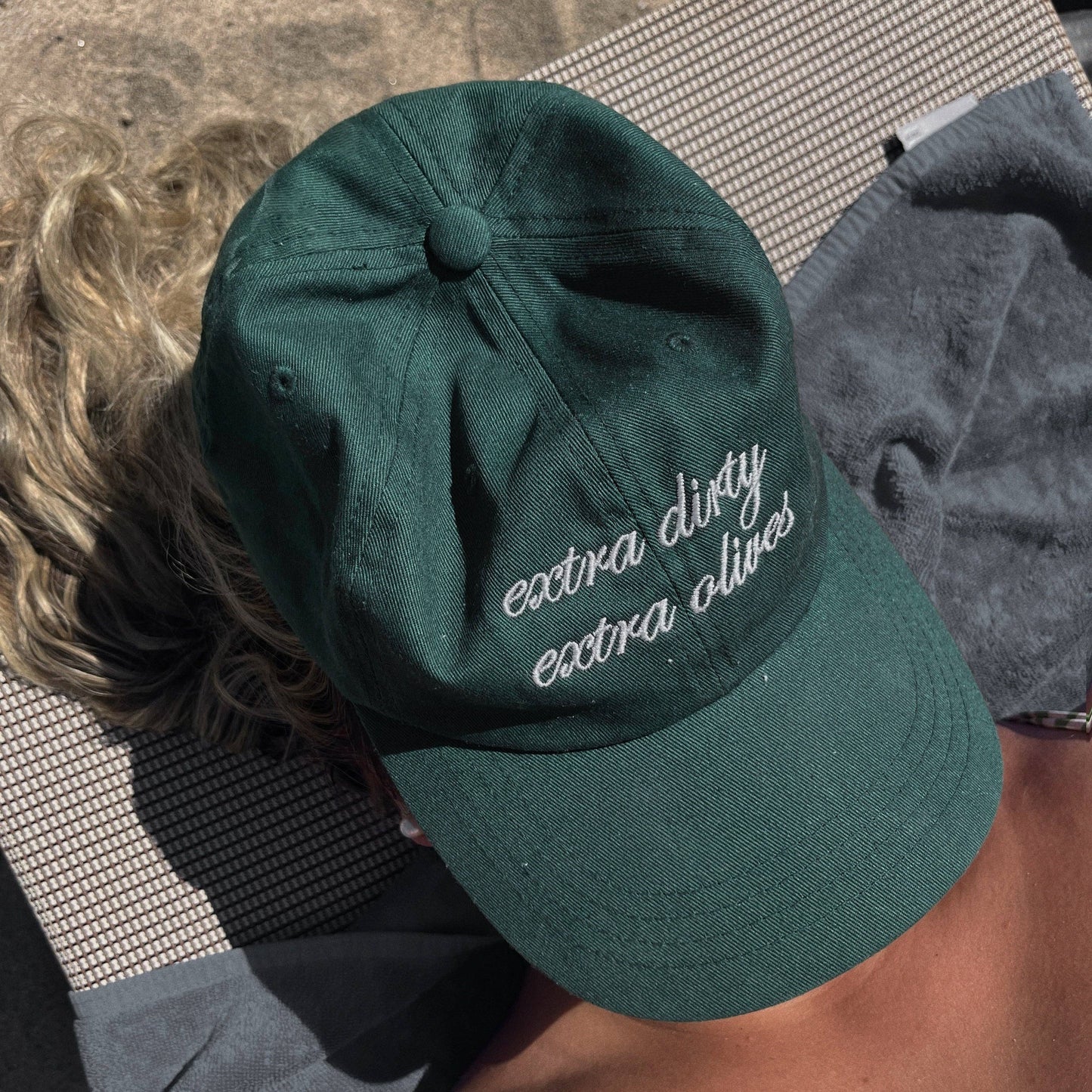 Green cap with text worn by a person on a towel