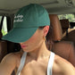 Person wearing a green cap with text inside a vehicle
