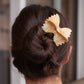 Hair claw made to look like a farfalle pasta. Pictured here holding up a person's hair 