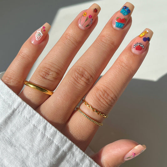 Close-up of a hand with colorful nail art on a neutral background