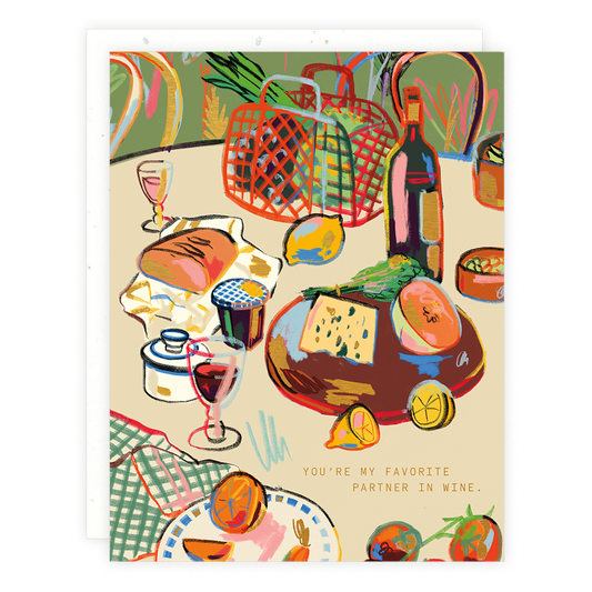 Greeting card with illustration of a table with a bottle of wine, glasses, bread, cheese and lemons among other things. Text reads "You're my favorite partner in wine." 