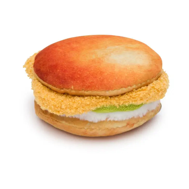 Side view of dog toy that looks like a fried chicken sandwich on a round bun.