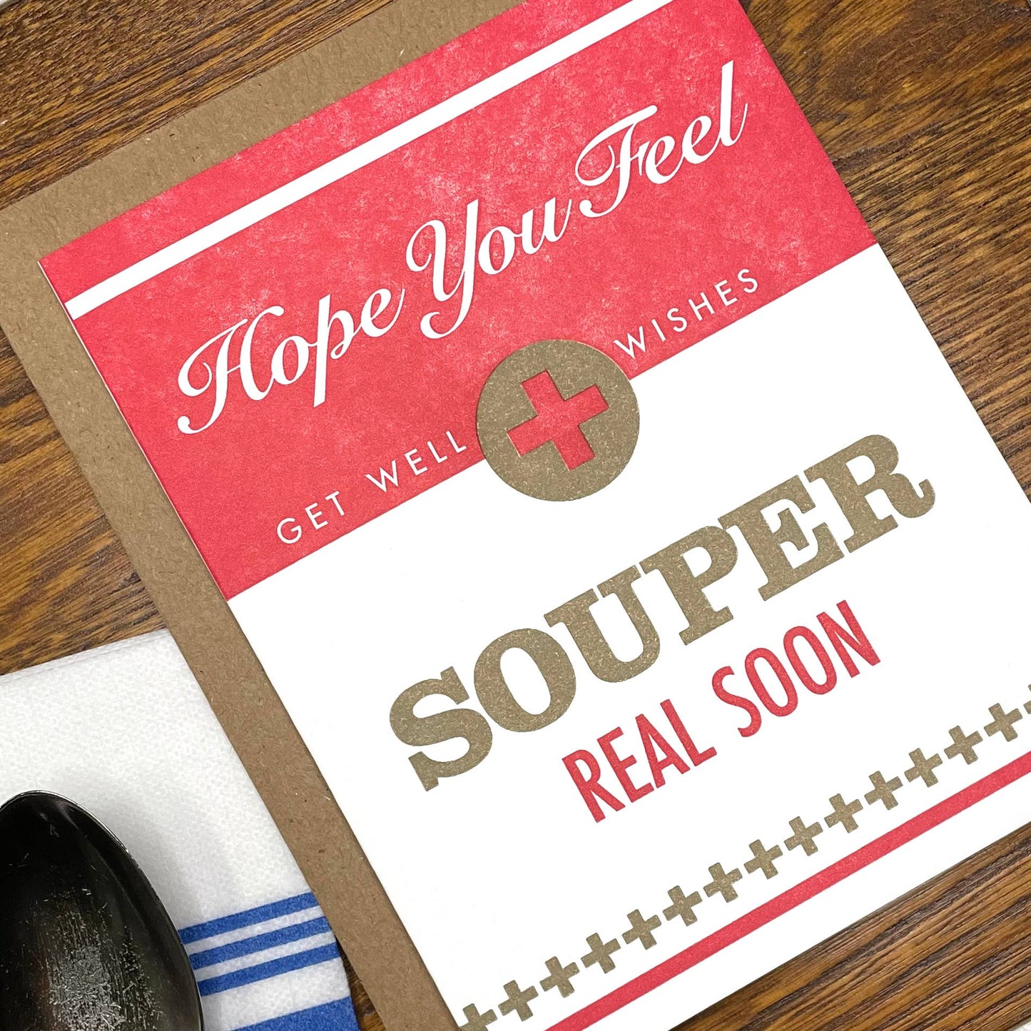 Get well card with text 'Hope you feel souper real soon' on a wooden surface