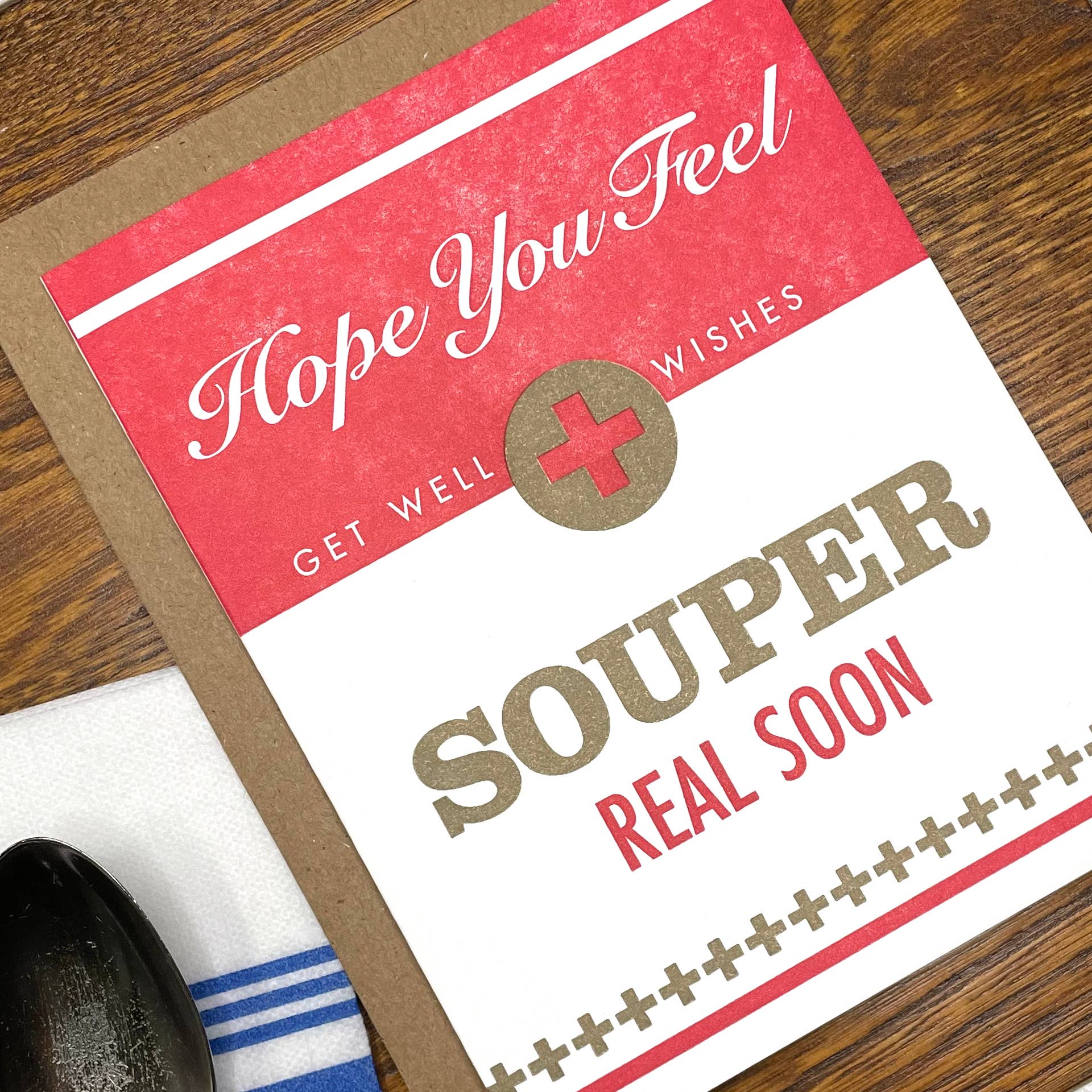 Get well card with text 'Hope you feel souper real soon' on a wooden surface