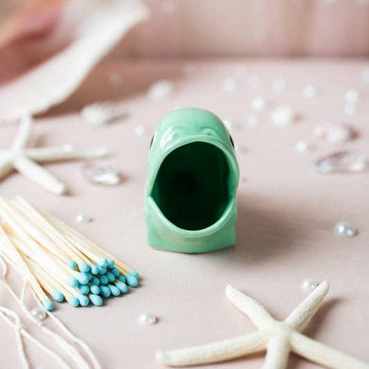Green ceramic container with starfish and pearls on a pink surface