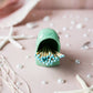 Green ceramic matchbox with matches on a decorative surface with starfish and pearls