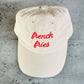 Beige cap with 'french fries' in red text on a concrete surface