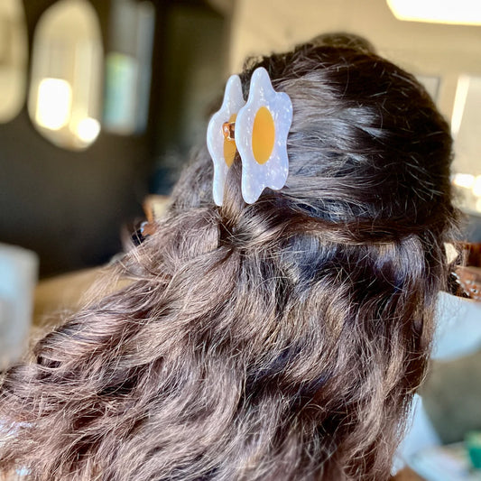 Girl with long brown hair wearing a fried egg hair clip.