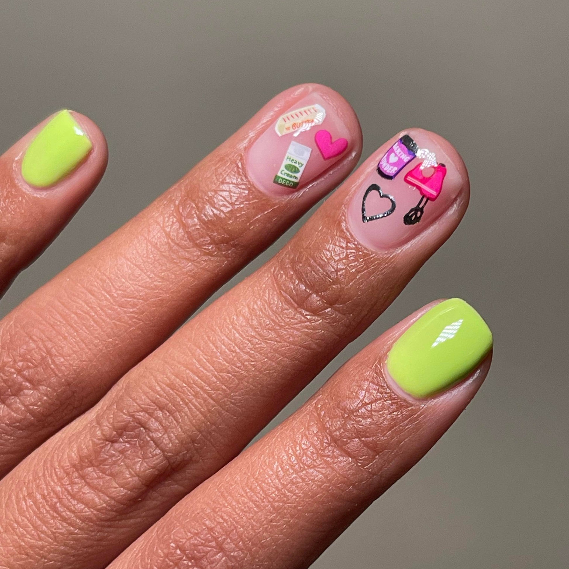 Hand with neon green nails and decorative stickers on a neutral background