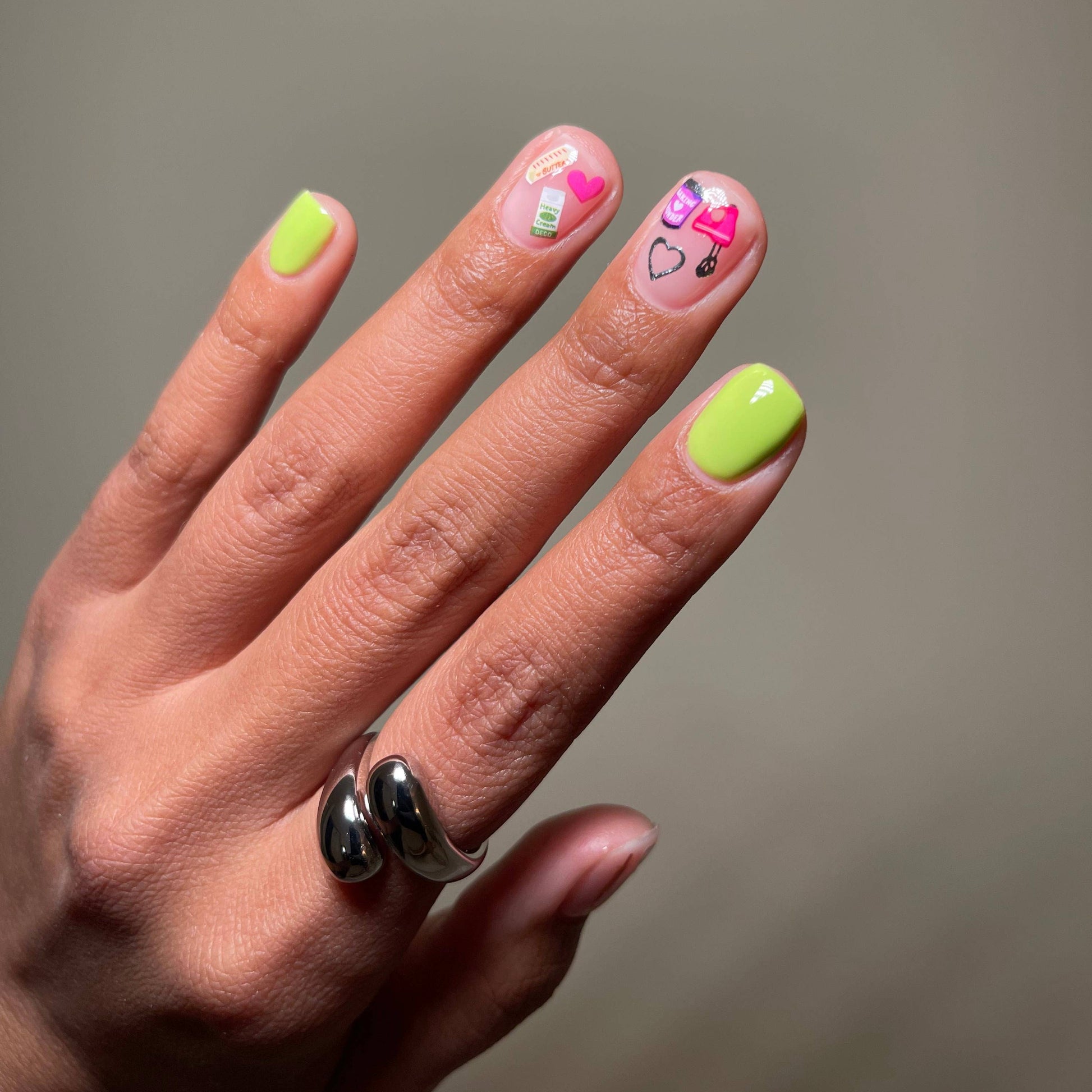 Hand with neon green nails and decorative nail art on a plain background