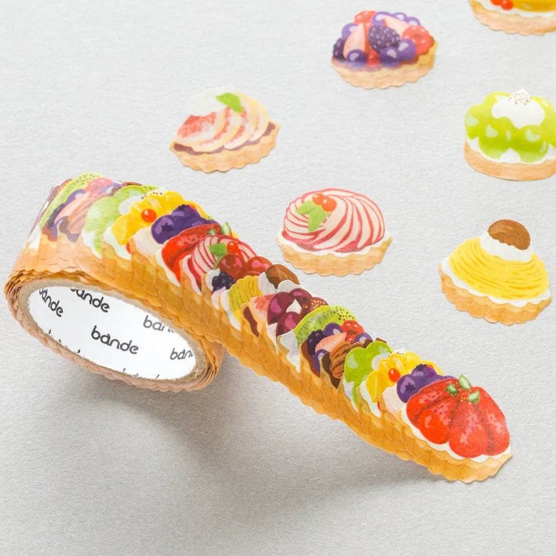 Roll of decorative washi stickers with fruit tart designs on a light gray background