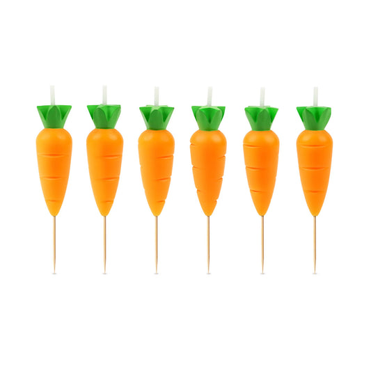 Set of carrot-shaped candles with green tops on a white background