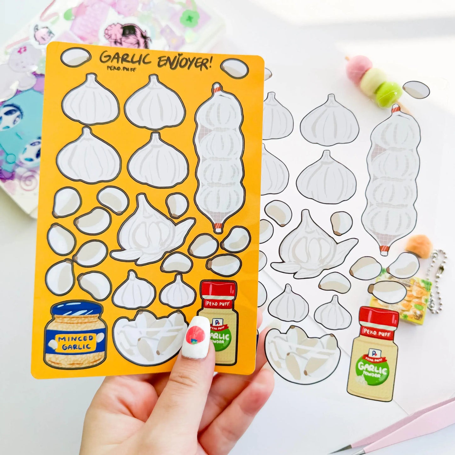 Sheet of garlic-themed stickers with a hand holding the sheet on a white background.
