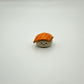 Small toy resembling a piece of sushi with a smiling face on a white background