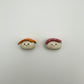 Two small ceramic sushi magnets, one salmon one tuna, with smiling faces on a light gray background