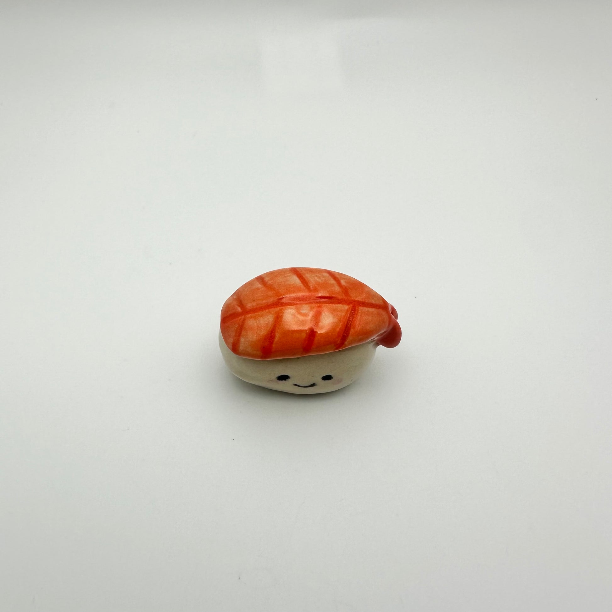 Small ceramic shrimp sushi with a smiling face on a white background