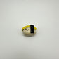 Small ceramic figurine resembling a piece of tamago/egg sushi on a white background