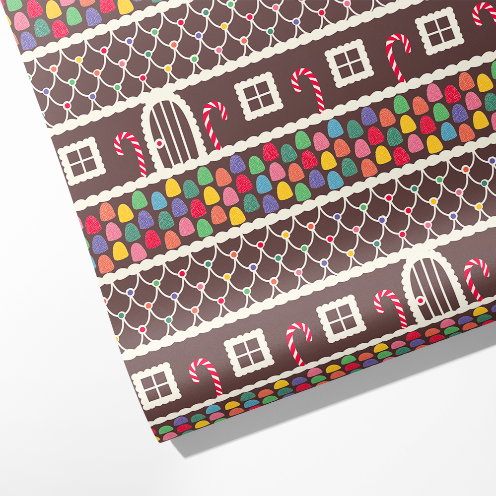 Roll of wrapping paper with a gingerbread house design and gumdrops and candy cane accents 