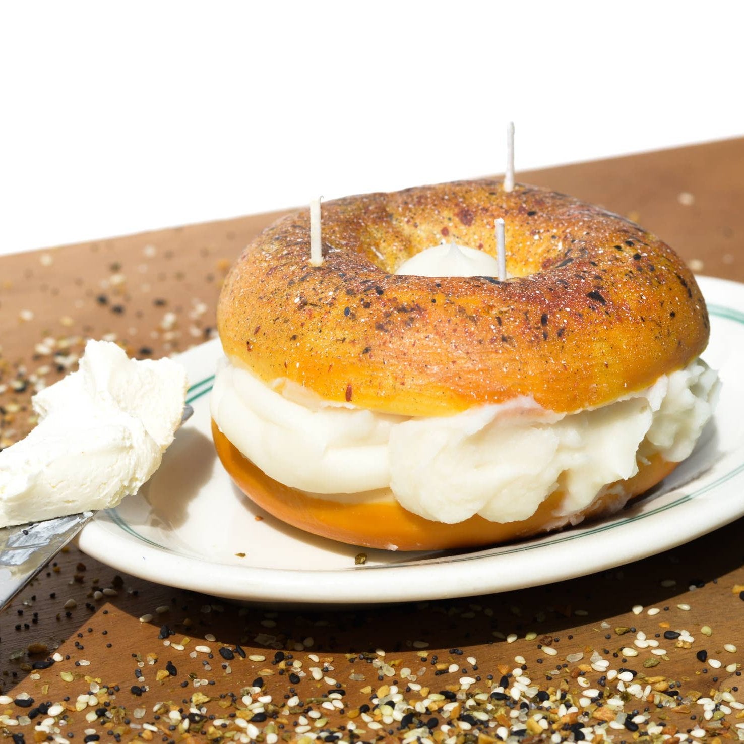 Everything bagel shown on a plate with a dinner knife full of real cream cheese.