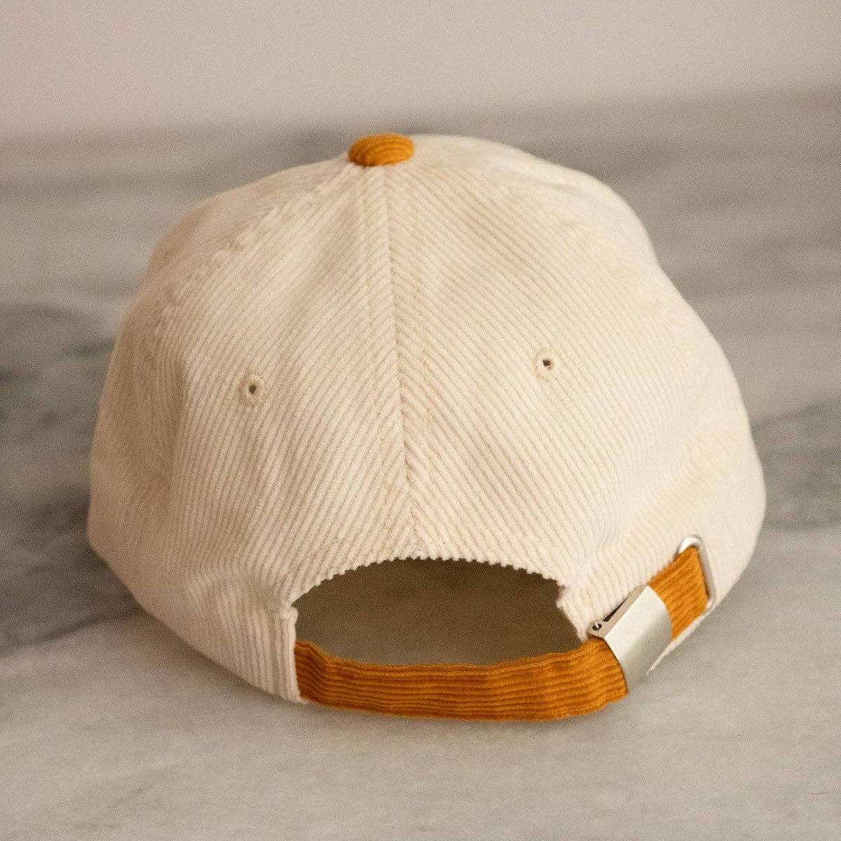 Beige cap with butterscotch brown accents on a gray surface
