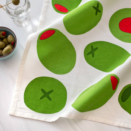 White towel with green olives pattern on a white surface