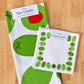 Tea towel and cocktail napkins with stuffed green olive designs on a wooden surface