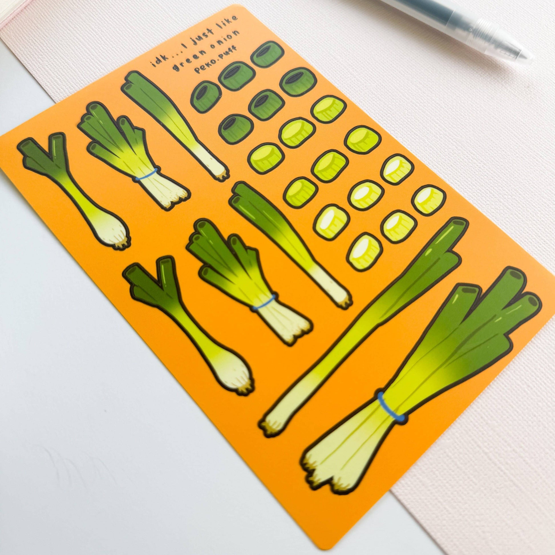 Sticker sheet of green onion stickers on an orange background