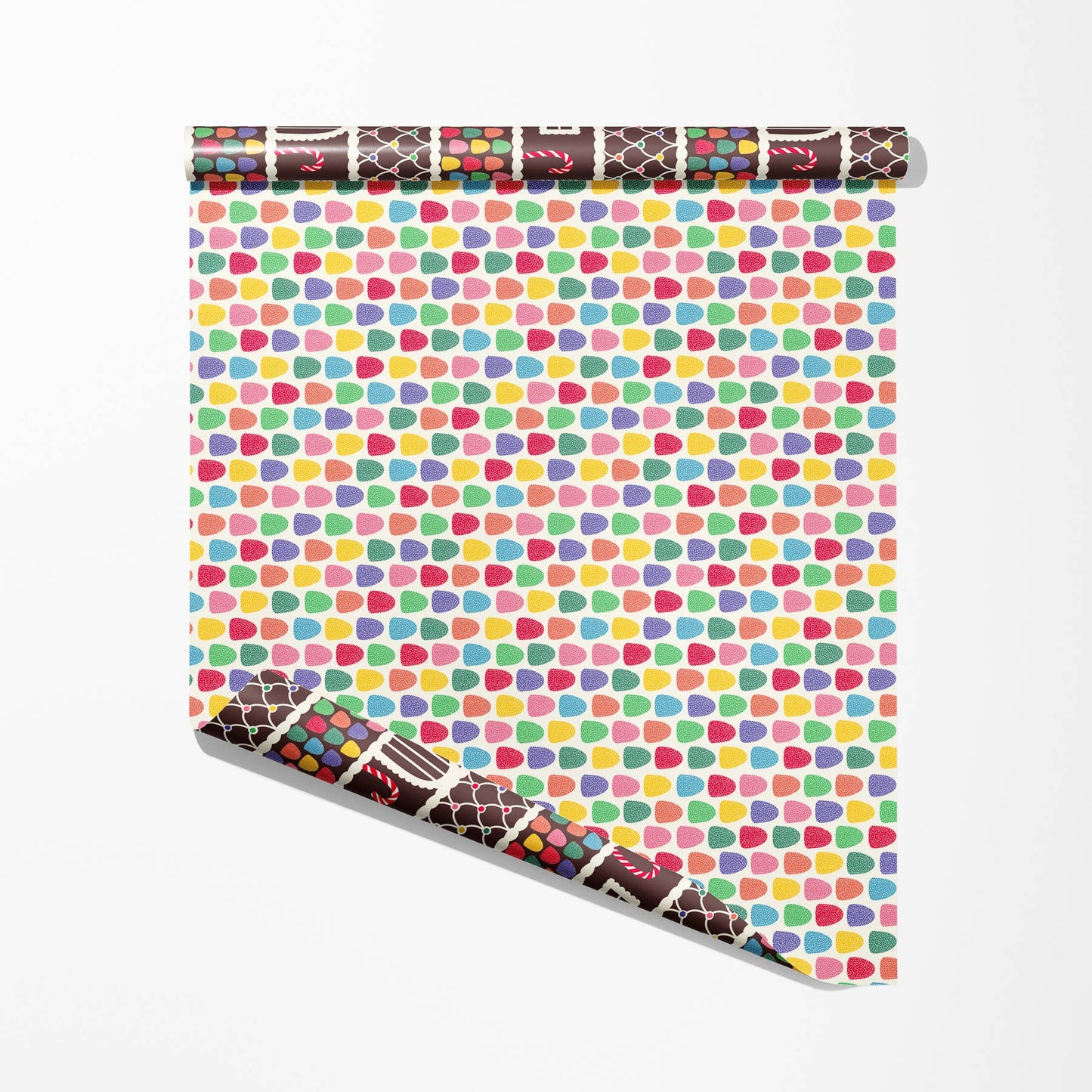 sheet of double sided gift wrap -- one side has a colorful repetitive gumpdrop design and the other has a decorated gingerbread house design 