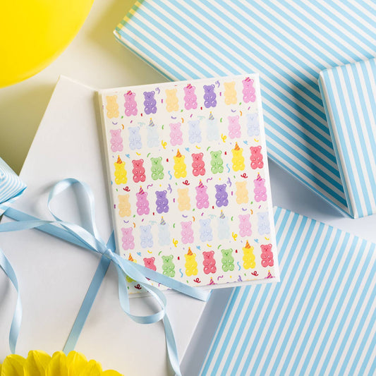 Greeting card with colorful gummy bear pattern on a white surface with blue ribbons and yellow balloons.