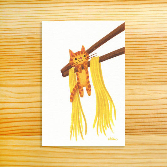 A vertical art print featuring a cute illustration of an orange tabby cat hanging from brown chopsticks with yellow noodles, displayed on a light wood grain background.