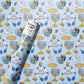 Gift wrap with Hanukkah-themed design featuring menorahs, dreidels, and 'Happy Hanukkah' text on a blue background.
