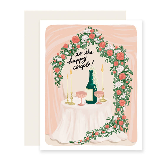 Wedding card with floral arch, champagne bottle, and 'to the happy couple!' text on a peach background.