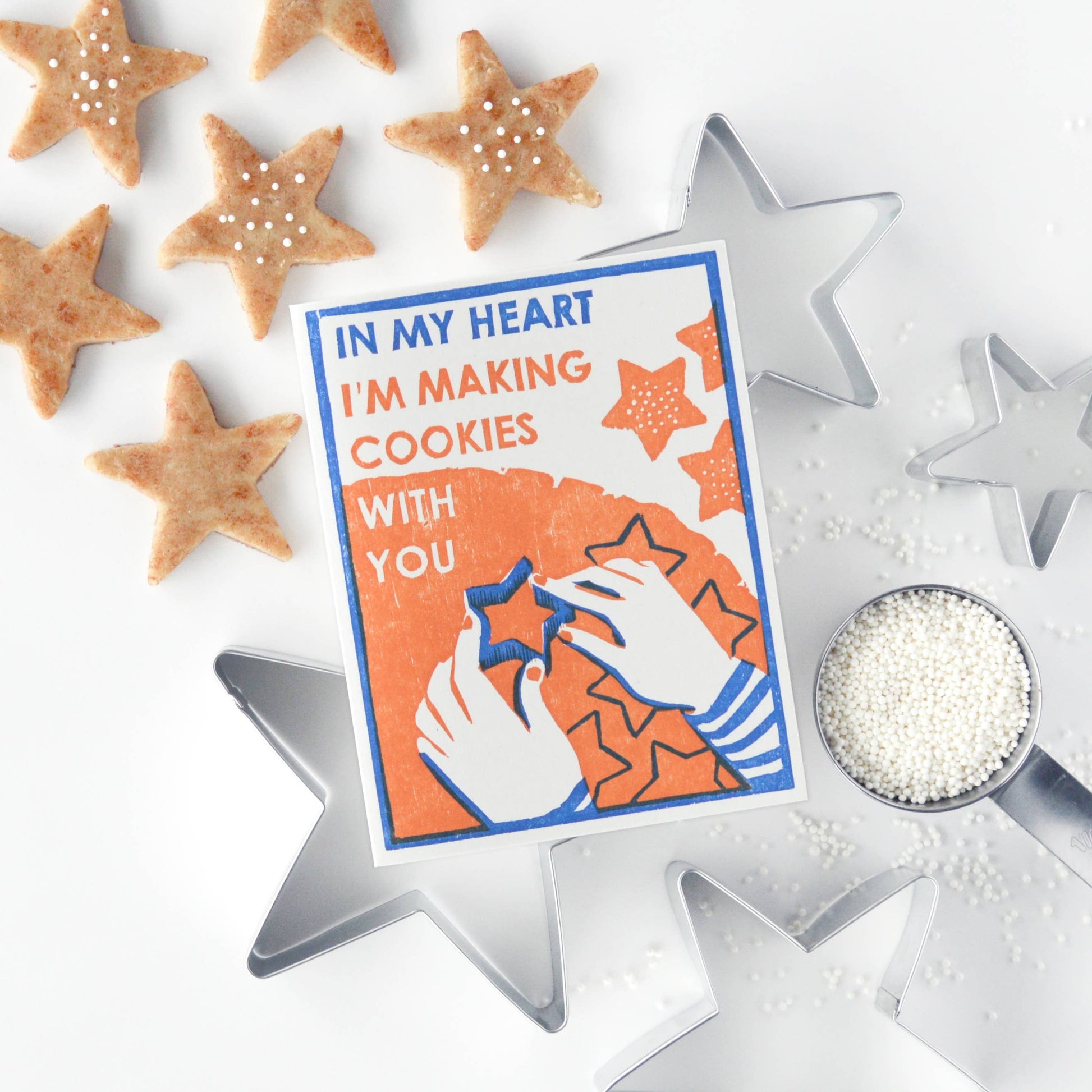 holiday greeting card that reads "in my heart I'm making cookies with you", sat on top of actual star cookie cutters