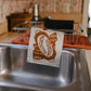the reusable bread pattern kitchen sponge cloth being dried on a dish drying rack 
