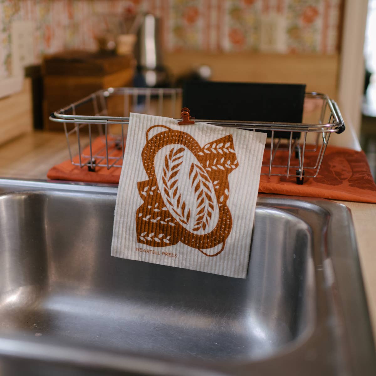the reusable bread pattern kitchen sponge cloth being dried on a dish drying rack 