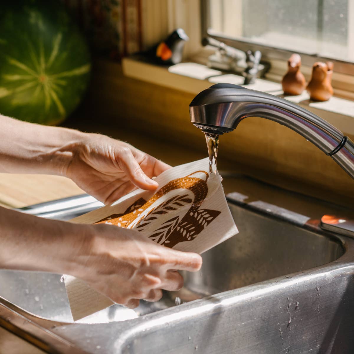 the reusable bread pattern kitchen sponge cloth being run under water to soften 