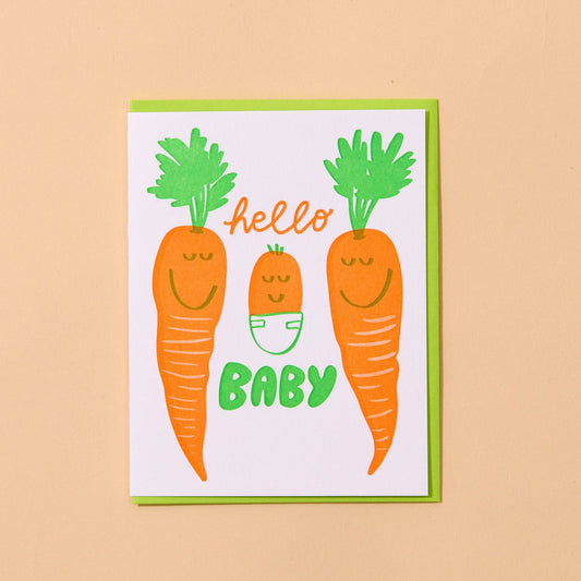 Card with cartoon carrots, 2 regular and one baby, and text 'hello baby' on a beige background