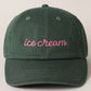 Green cap with 'ice cream' embroidered in pink on a beige background