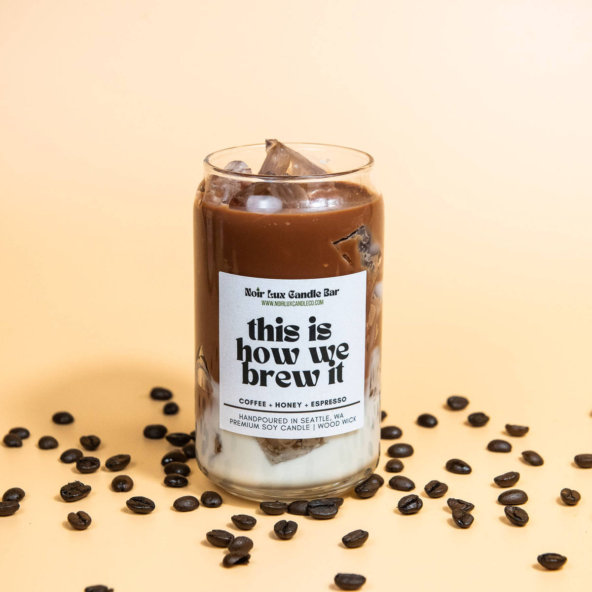 Candle labeled 'this is how we brew it' with coffee beans on a beige background