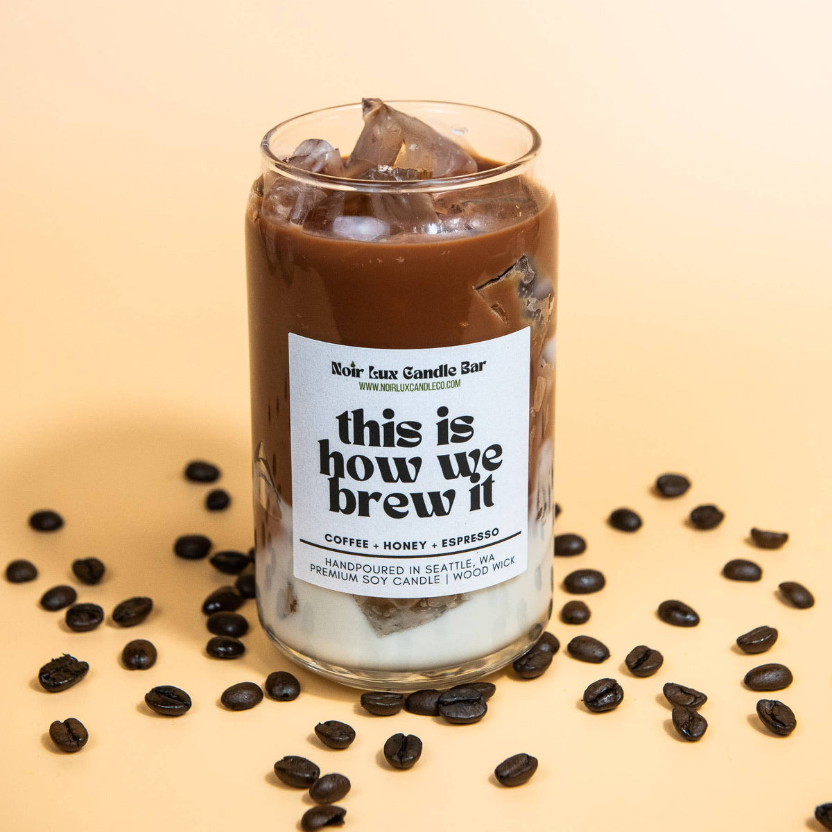 Glass of iced coffee with coffee beans on a beige background