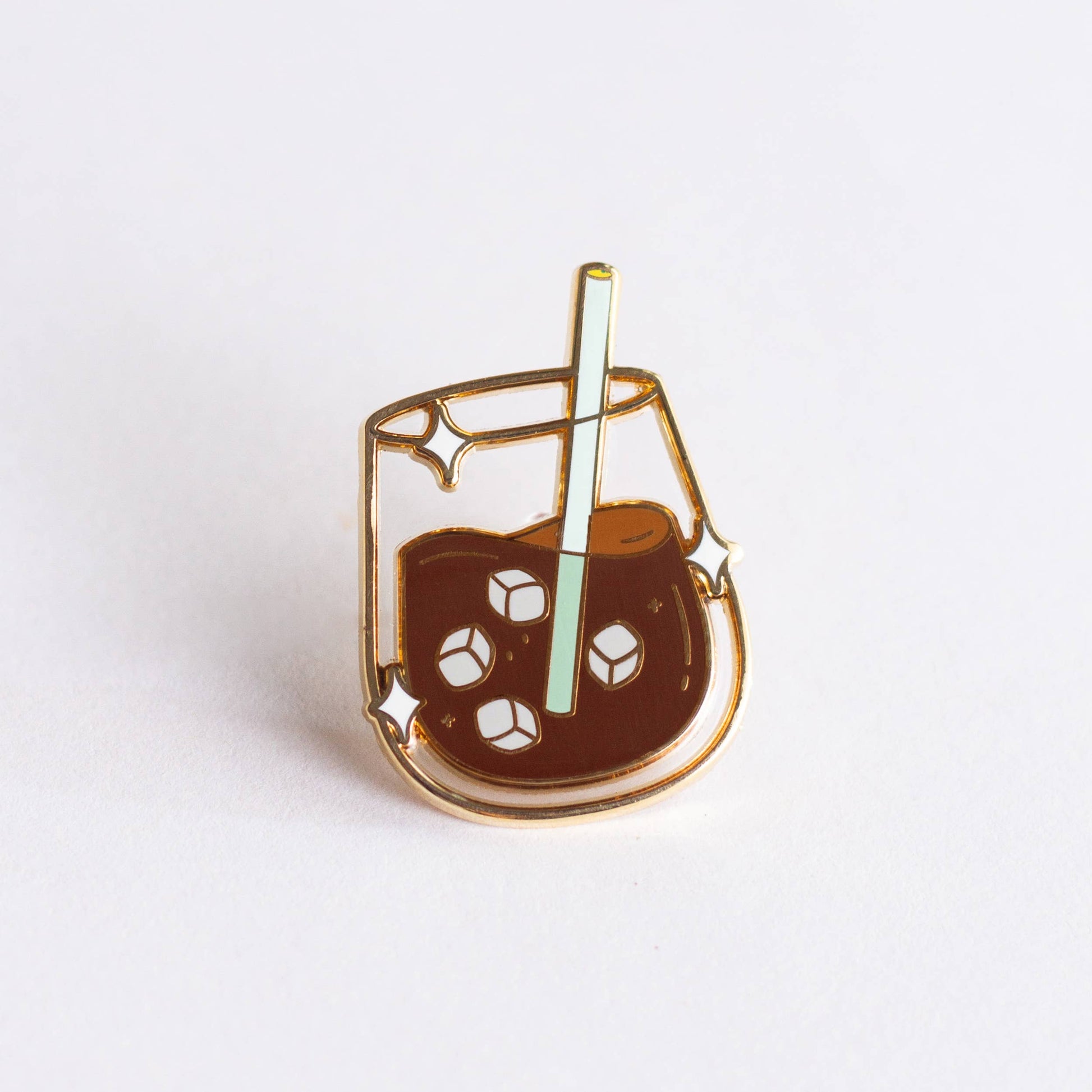 Enamel pin of a glass of iced coffee with a straw on a white background