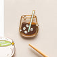 Enamel pin of a glass of iced coffee with a straw on a beige background