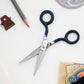 Photo of scissors next to other office supplies.