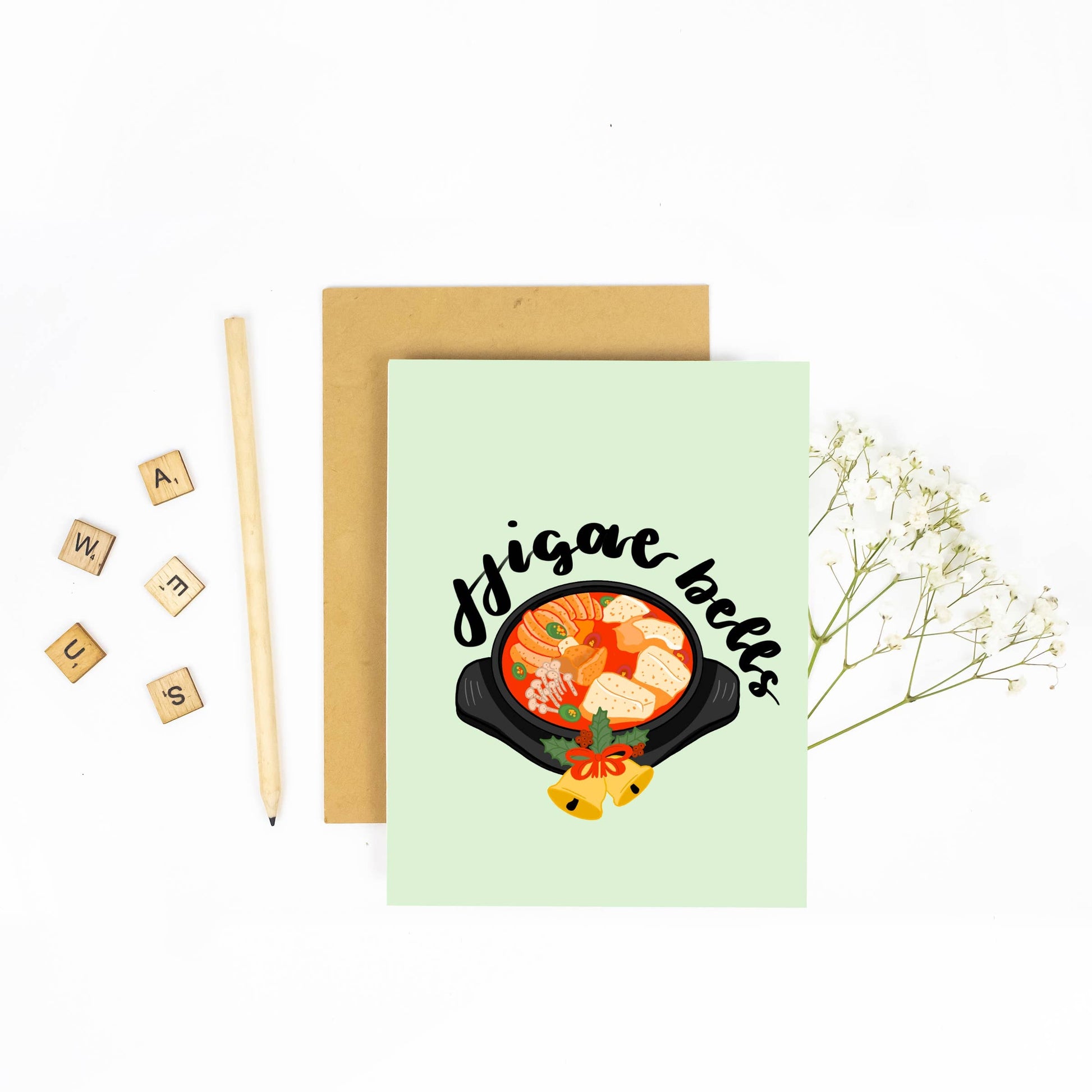 Holiday greeting card that has an illustration of a pot of kimchi jjigae on it with text that reads "Jjigae bells"