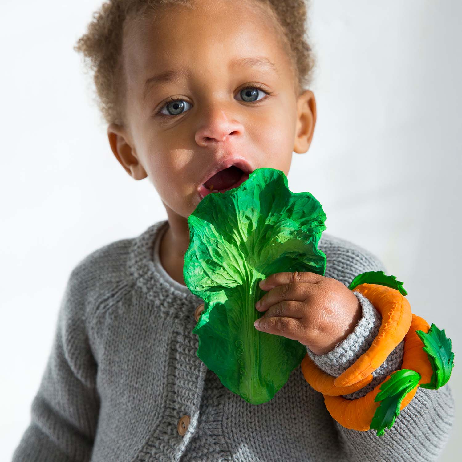 Photo of baby biting into kale baby toy.