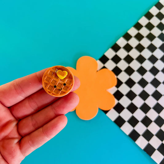 mini smiley faced waffle magnet with a heart-shaped pad of butter and syrup on it