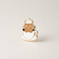 Cat-shaped pin in a tea/coffee cup on a beige background