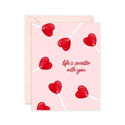 Greeting card with red heart lollipops and 'life's sweeter with you' text on a pink background