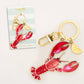 Lobster with lemon wedge keychain with gold accents on a white background